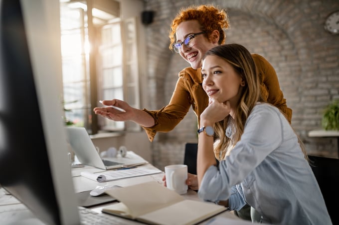 happy-female-entrepreneurs-reading-email-computer-while-working-together-office-focus-is-redhe